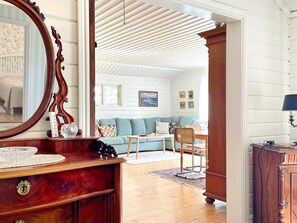 Een kamer met een houten bureau, een grote spiegel, een bank en een eethoek.