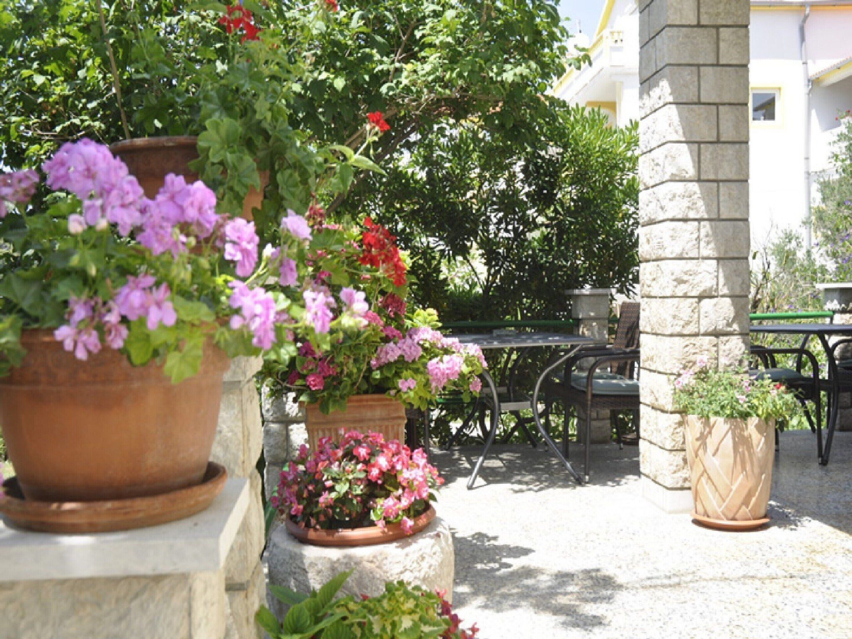 A patio area with outdoor seating, potted plants, and a stone wall.