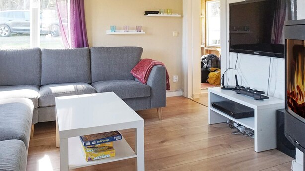 A living room with a grey sofa, a white coffee table, a flat-screen TV, and a fireplace. - 6 Person Holiday Home in Fjallbacka (Fjallbacka)