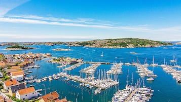 Un puerto deportivo con barcos amarrados, rodeado de edificios y un paisaje montañoso.