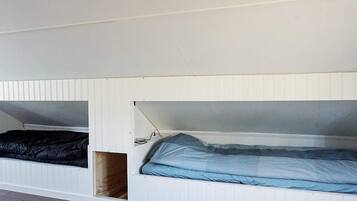 A room with two bunk beds, one with a black mattress and the other with a blue mattress.