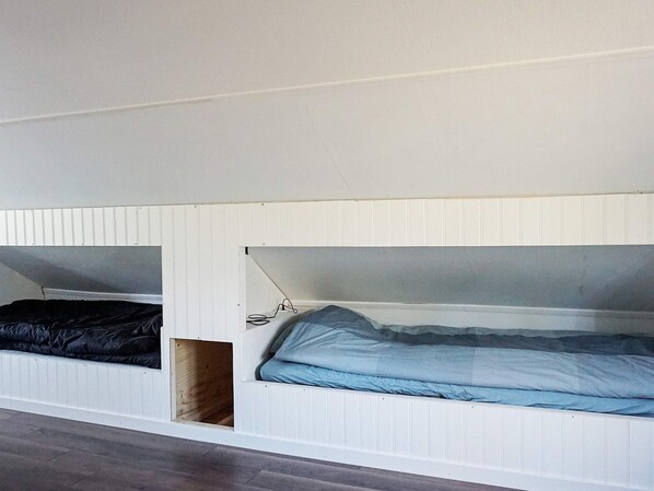 A room with two bunk beds, one with a black mattress and the other with a blue mattress.