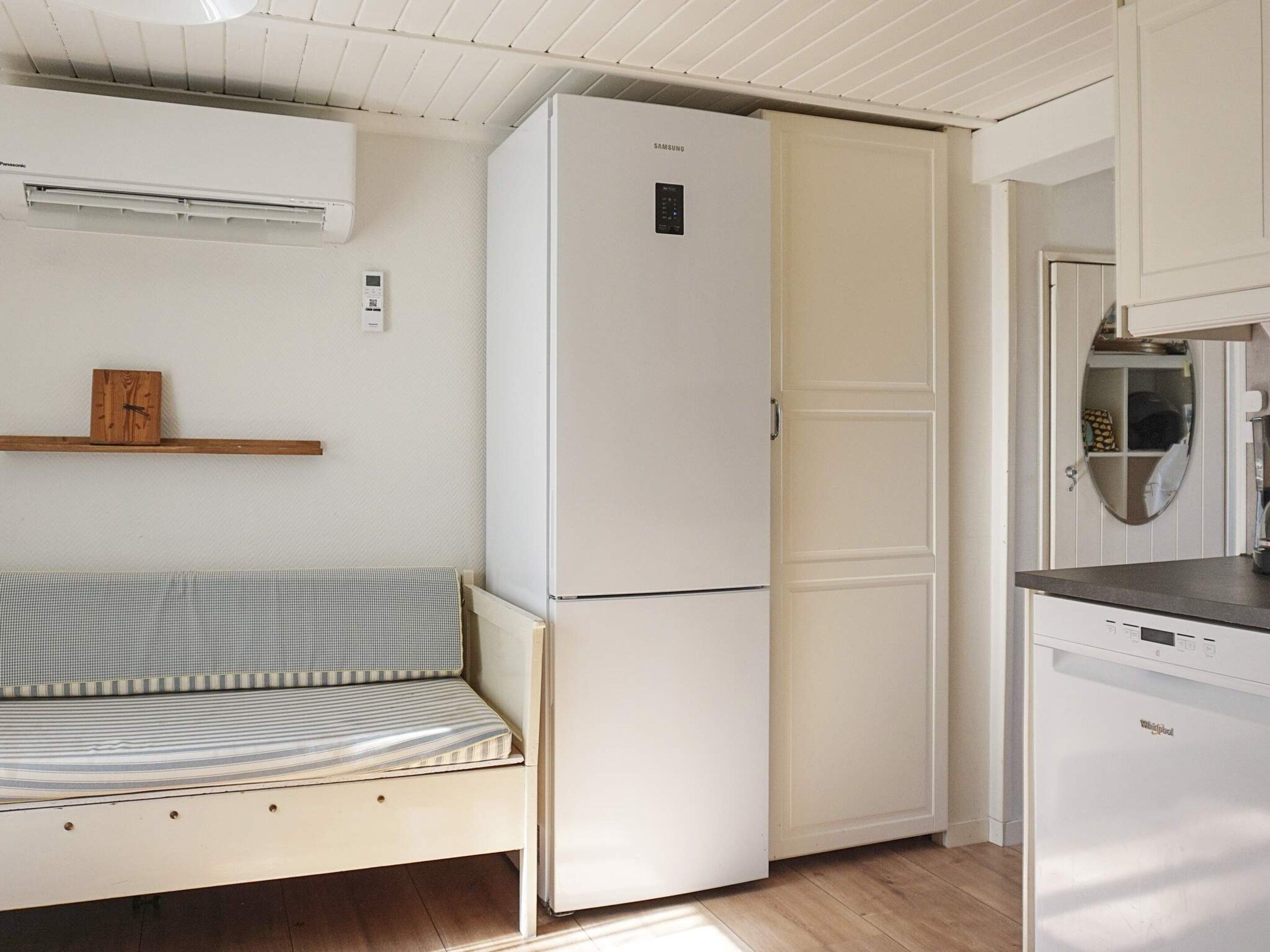 A compact kitchen with a white refrigerator, a small bench, and a dishwasher.