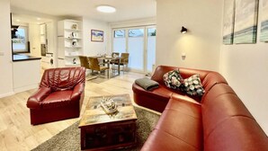 A modern living room with a red leather sofa, a coffee table, and a dining area with a table and chairs.
