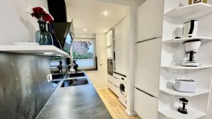 A modern kitchen with a dark countertop, built-in appliances, and white cabinetry.