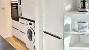 A modern kitchen with built-in appliances, including a washing machine, oven, and coffee maker.