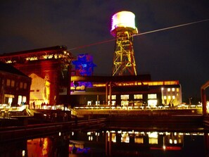 A waterfront building with a prominent tower, a bridge, and a reflection in the water. - Holiday Apartment Anderewelt-bochum (Bochum)