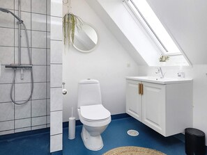 Enjoy a refreshing shower with a handheld hose in this bathroom, featuring a sink with a mirror above and a toilet.