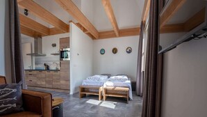 Una habitación funcional con dos camas, kitchenette y zona de comedor.