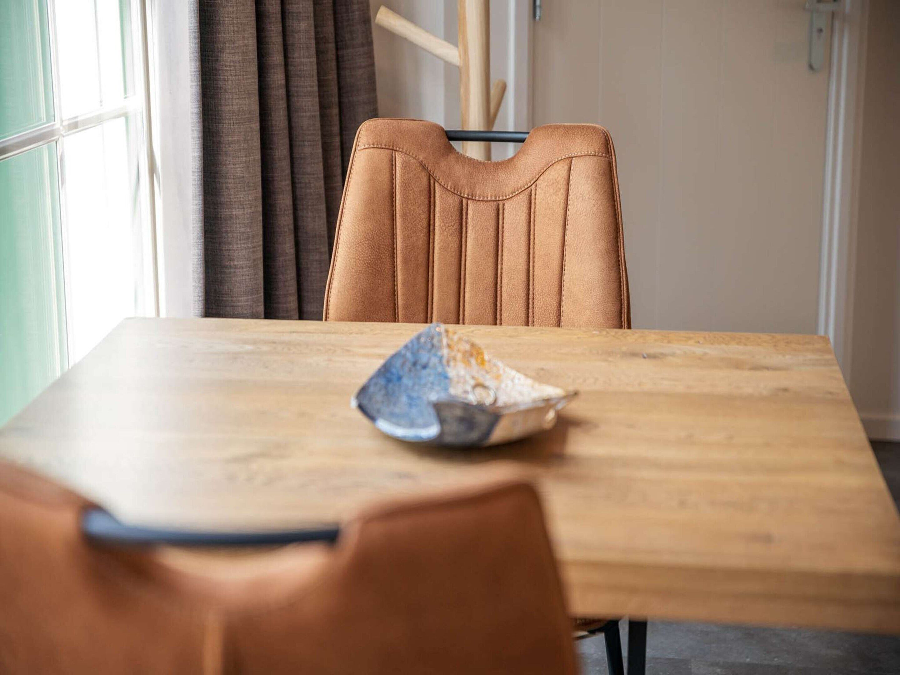 A dining area with a wooden table and a single brown chair.
