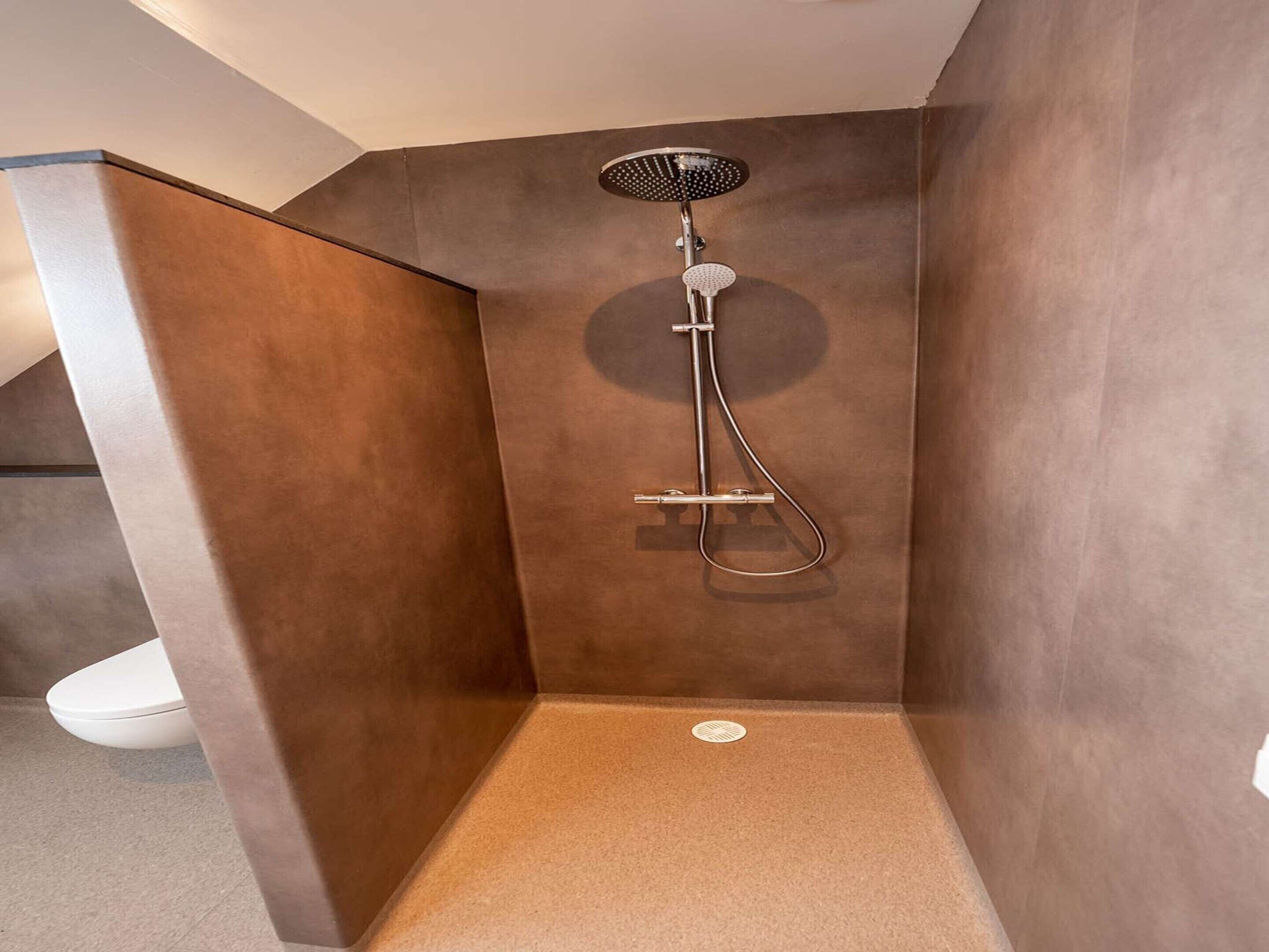 A modern shower with a handheld showerhead and a handheld hose.