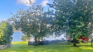 A grassy area with trees and a body of water in the background. - 7 Person Holiday Home in Tjorn-by Traum (Myggenäs)
