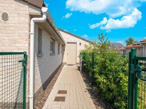 A corridor with a brick wall, a beige door, and a green gate. - Holiday Home in Koksijde Near Sint-andre Beach (Koksijde)