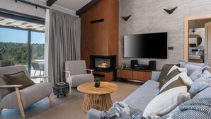 Una sala de estar moderna con chimenea, un televisor de pantalla plana grande y un sofá con muchos cojines.