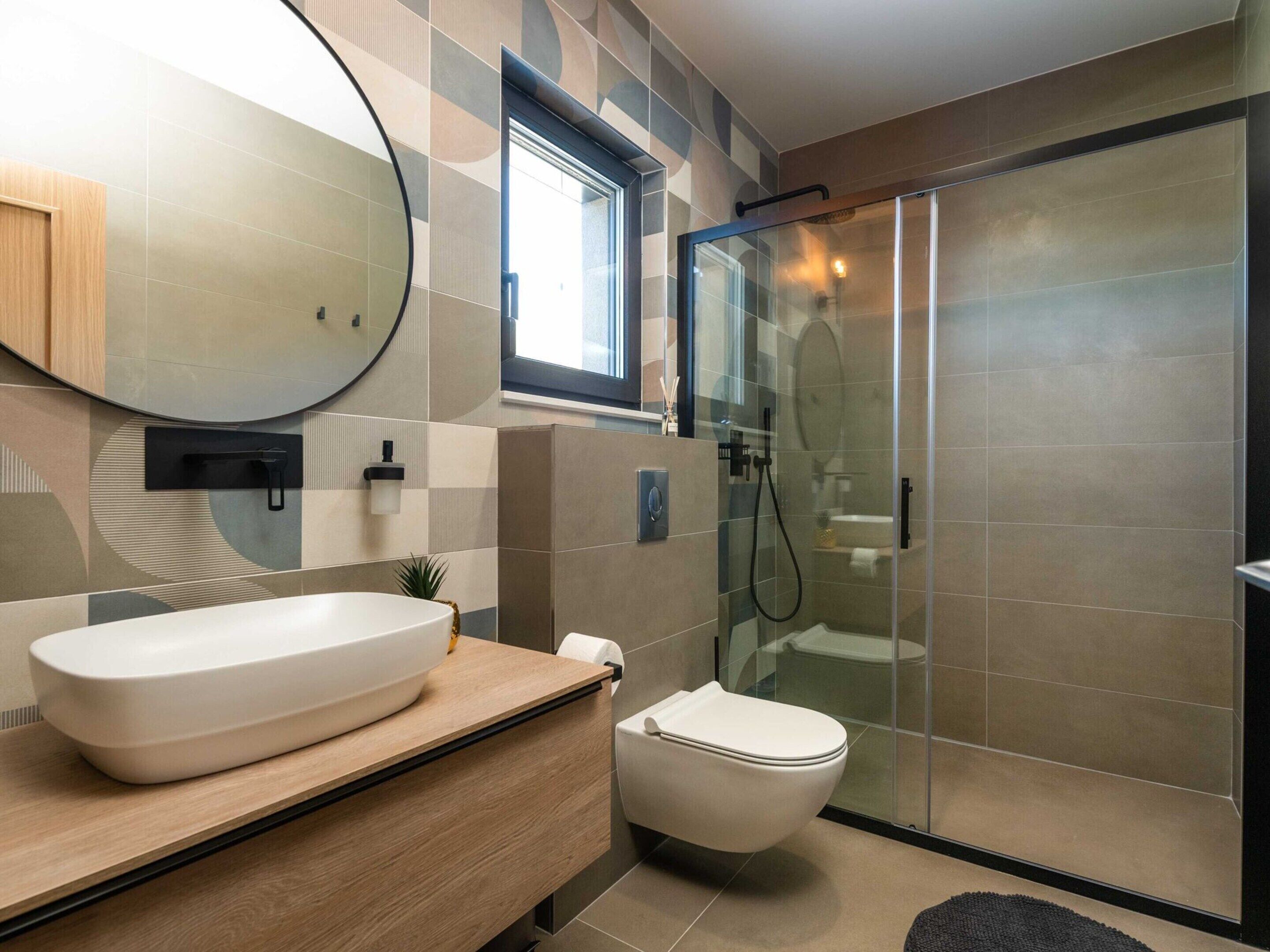 A modern bathroom with a large oval sink, a toilet, and a glass-enclosed shower area.