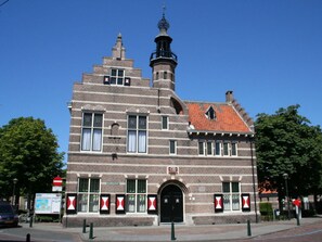 A historic building with a prominent tower, arched windows, and a red-tiled roof.
