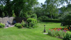 A well-maintained garden with a lawn, a seating area with chairs, and a variety of plants and flowers. - Jessen Modern Retreat (Gelting)