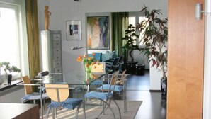 Eine moderne Küche mit Essbereich, ausgestattet mit einem Glastisch, Metallstühlen und einem Holzkasten.