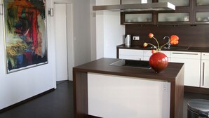 Eine moderne Küche mit einer zentralen Kochinsel, einer Kaffeemaschine und einer Vase mit Blumen.