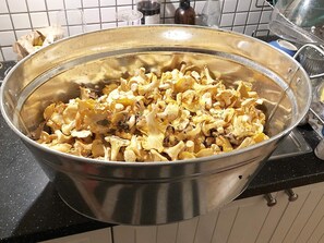 Un tazón metálico grande lleno de hongos sobre una encimera de cocina.