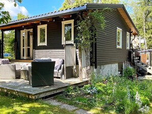 Una cabaña de madera con porche, mobiliario exterior y un jardín.