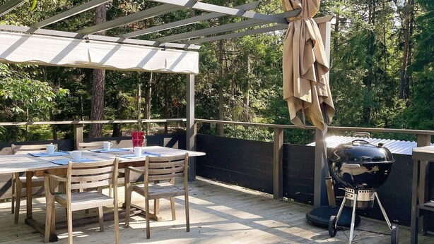 An outdoor patio with a wooden table and chairs, a barbecue grill, and a pergola with a canopy. - 5 Person Holiday Home in Djurhamn-by Traum (Djurhamn)