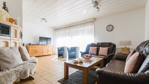 Ett vardagsrum med en soffa, fåtöljer, ett soffbord och en tv.