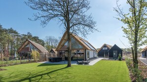 Ein modernes Haus mit großer Glasfassade, gepflegtem Rasen und einem Baum in der Mitte.