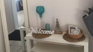A white console table with a 'Welcome' sign, a small Christmas tree, and a framed picture on the wall. - Bungalow at Galgenberg in Wernigerode (Wernigerode)