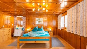 L’intérieur d’un chalet en bois comprend un lit, une salle de bain et une fenêtre avec des rideaux.
