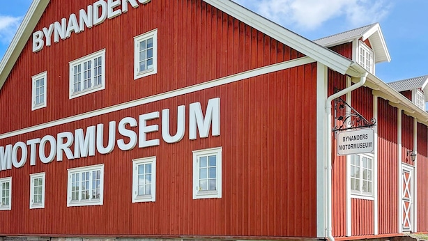 Een rood gebouw met de tekst 'BYNANDERS MOTORMUSEUM' op de gevel.