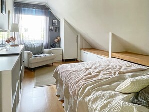 Un dormitorio con cama, escritorio, silla y ventana con cortinas.