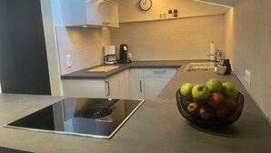 A modern kitchen with a built-in induction cooktop, a coffee maker, and a fruit bowl on the counter. - 1 Porzig Modern Retreat (Fischen im Allgaeu)