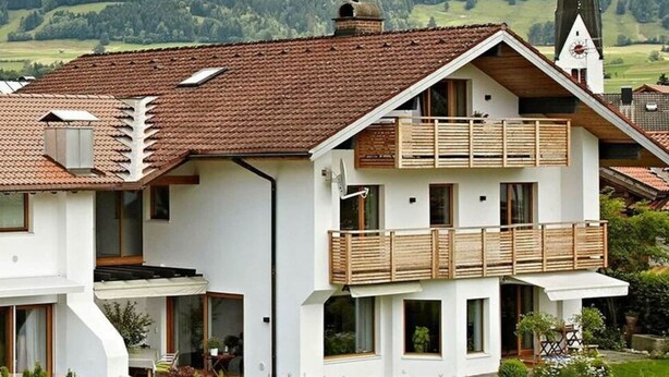 A modern two-story house with a red-tiled roof, white exterior walls, and wooden balconies. - 1 Porzig Modern Retreat (Fischen im Allgaeu)