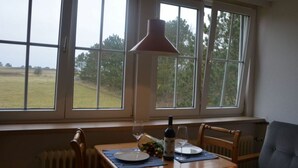 Un coin repas avec une table mise pour deux, une bouteille de vin et une lampe.