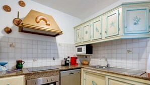 Cozinha com painel de azulejos brancos, eletrodomésticos de aço inoxidável e armários azul claro com detalhes decorativos.