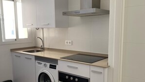 Une cuisine compacte équipée d’un lave-linge, d’un four et d’une plaque de cuisson intégrée.