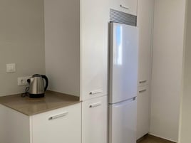 Une cuisine avec un réfrigérateur blanc, une bouilloire et un plan de travail.