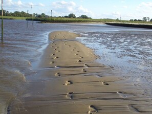 Ein Sandstrand mit Fußspuren, die ins Wasser führen.