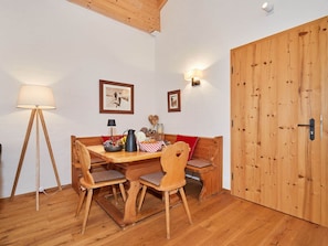 Una mesa de comedor de madera con cuatro sillas, una lámpara de pie y un banco con cojines.