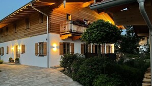 A two-story wooden house with a balcony and a paved driveway. - Holiday Apartment Dosbach (Reit im Winkl)