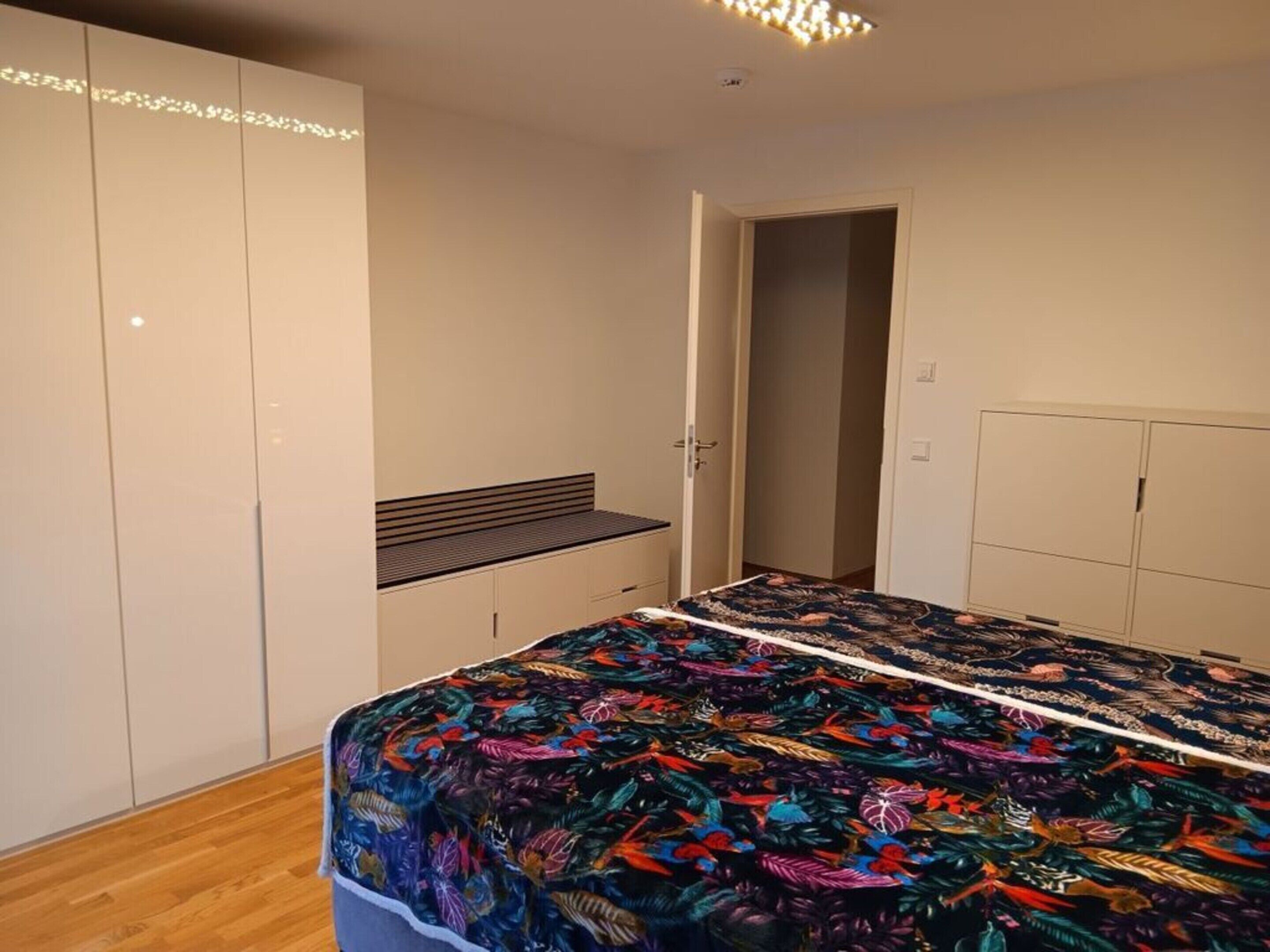 A bedroom with a bed, wardrobe, and a bench.