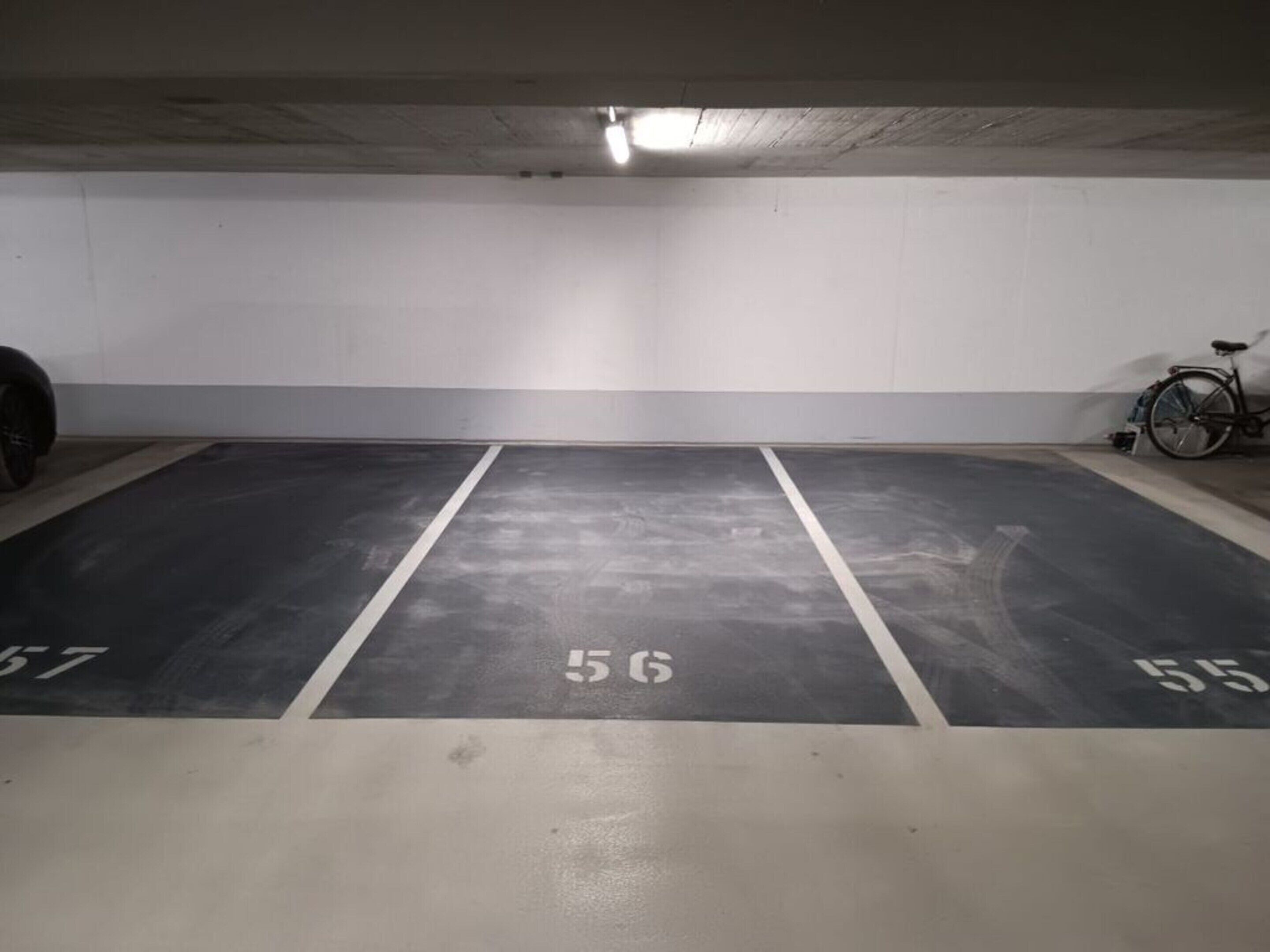 Eine Parkgarage mit drei markierten Stellplätzen, nummeriert 56, 55 und 57.