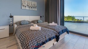 Une chambre moderne avec deux lits, une grande fenêtre et un tableau représentant un voilier accroché au mur.