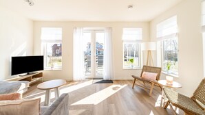A spacious living room with a flat-screen TV, comfortable seating, large windows, and a view of the outside. - Holiday Home With Lots of Privacy (Simonshaven)