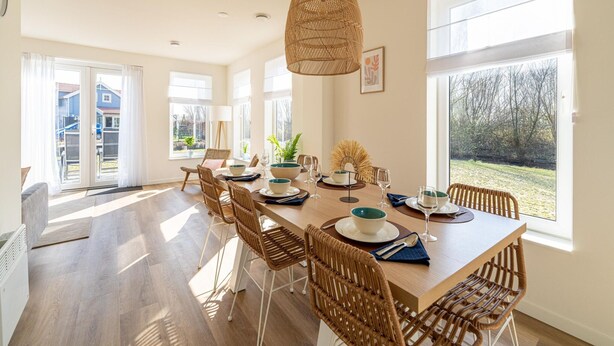 A dining area with a long table, wicker chairs, and a hanging light fixture. - Holiday Home With Lots of Privacy (Simonshaven)