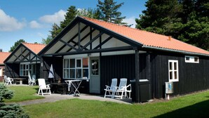 Un bâtiment à deux étages, doté d’un toit recouvert de tuiles rouges et d’un balcon. On y trouve des chaises et une table blanches à l’extérieur.