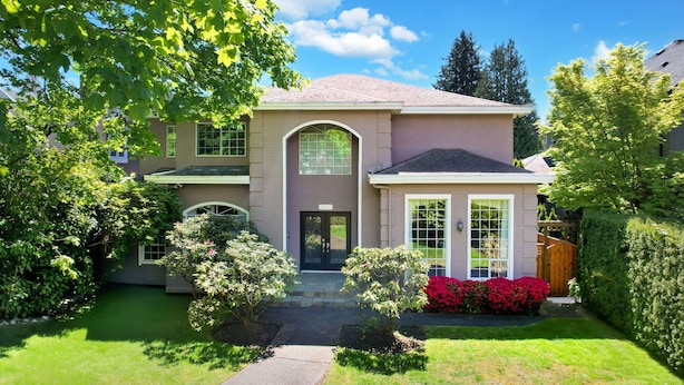A two-story house with a front entrance, a covered porch, and a well-maintained lawn.