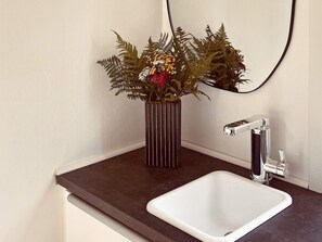A bathroom with a white sink, a modern faucet, and a decorative plant in a striped vase. - 4 Star Holiday Home in Varberg (Varberg)