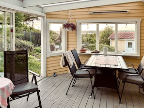 A covered patio with a wooden table and chairs, a hanging flower pot, and a view of the surrounding area. - 4 Star Holiday Home in Varberg-by Traum (Varberg)